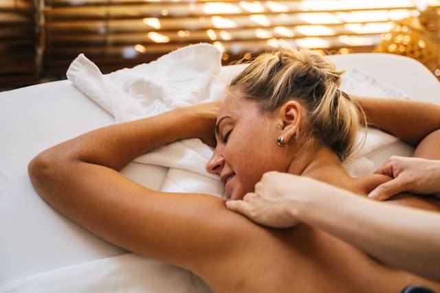 Woman receiving a massage on a table in a spa-like setting at Arlington Physical Therapy for relaxation and self-care.