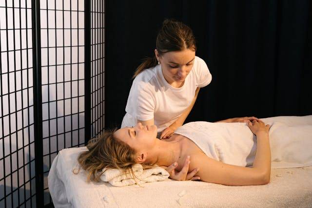 Two women in professional attire perform a massage on a table with towels at Arlington Physical Therapy.